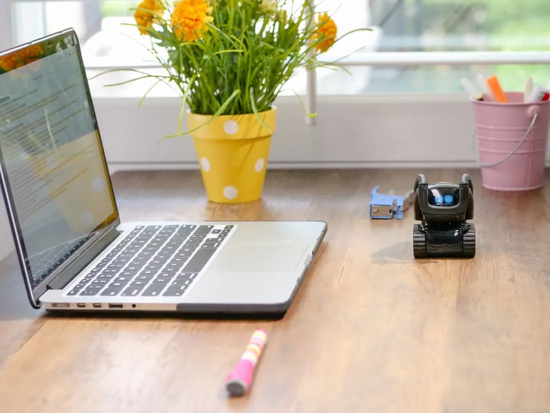 Mesa de trabalho com laptop e pequeno robo decorativo